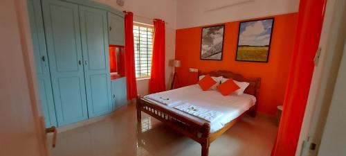 a bedroom with orange walls and a bed with red pillows at Orange Valley Homestay Trivandrum in Trivandrum