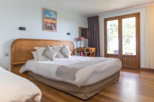 Un dormitorio con una gran cama blanca y una ventana en Les Géraniums, en La Plaine des Cafres