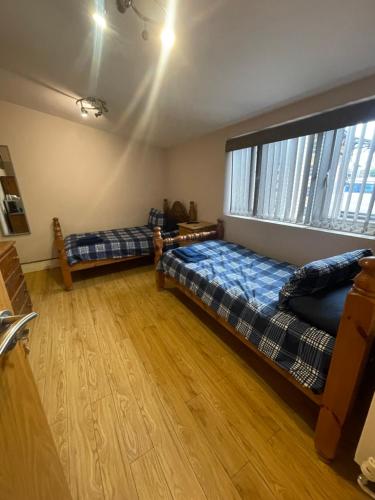 a bedroom with two beds and a large window at Abbey Guest House in Milton Keynes