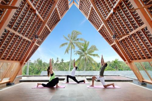 een groep mensen die yoga doen in een paviljoen bij Kaamala Resort Ubud by Ini Vie Hospitality in Ubud