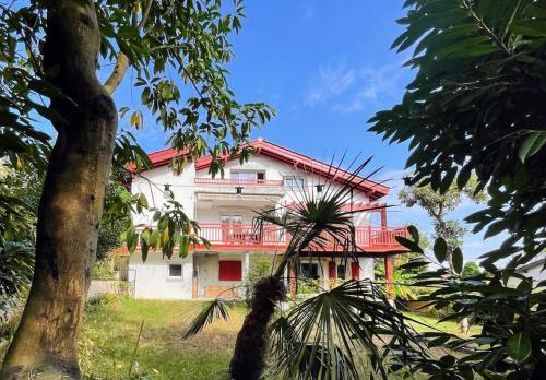 - un bâtiment blanc avec un balcon rouge et un arbre dans l'établissement Lagunen etxea, à Hendaye