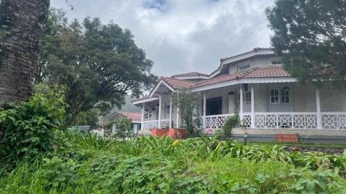 a large white house with a large porch at Bruton resorts in Kodaikānāl