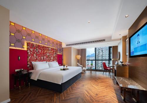 ein Hotelzimmer mit einem Bett und einem Flachbildfernseher in der Unterkunft Zhangjiajie Metropolo Hotel in Zhangjiajie