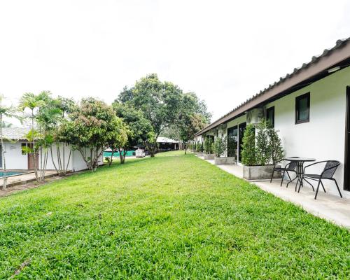 a yard with tables and chairs next to a building at Apollo Hotel Chalong in Ban Suan