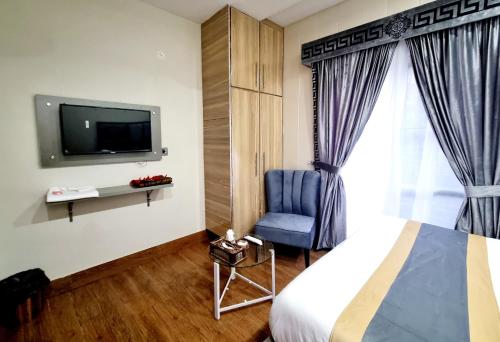 拉合爾的住宿－Hotel Grand Pakeeza，一间卧室配有一张床、一台电视和一把椅子