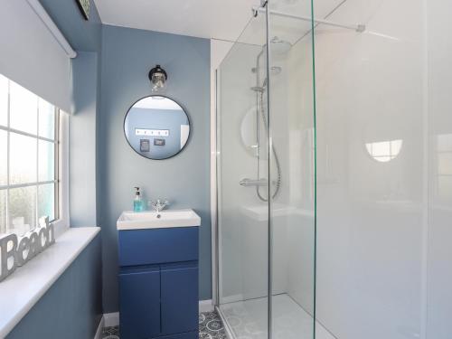 La salle de bains est pourvue d'une douche, d'un lavabo et d'un miroir. dans l'établissement The Old Coach House, à Beaumaris