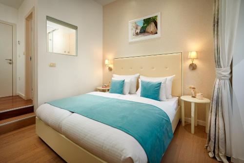 a bedroom with a large bed with blue and white pillows at Olea Luxury Rooms in Split