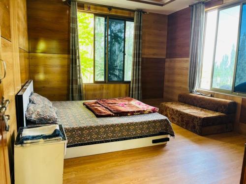 a bedroom with a bed and a couch and windows at Pacific guest house in Skardu