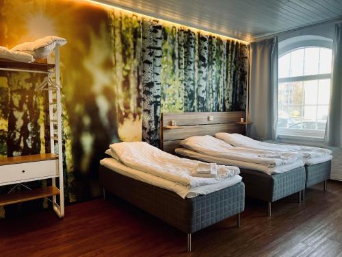ラウマにあるHotel Sleep at Raumaのベッド3台と窓が備わる客室です。