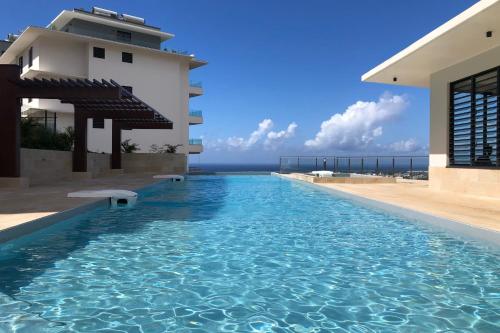 einem Pool vor einem Gebäude mit Meerblick in der Unterkunft Heiata Sky apartment 3 bedr in Papeete pool & gym garden Wi-Fi Netflix in Papeete