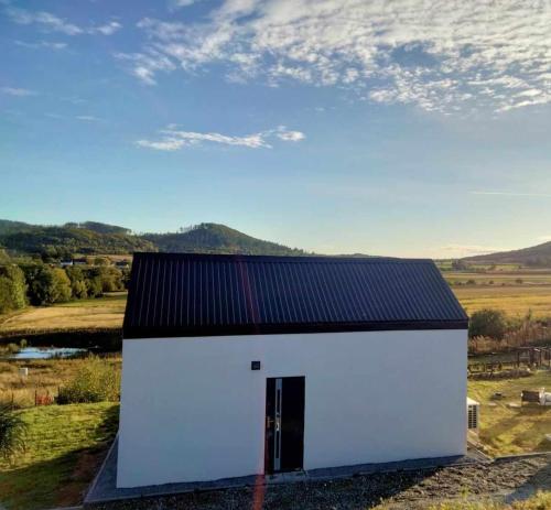 a white building with a black roof at WIDOKOVO - Relax, cisza,widoki, sauna & jacuzzi wliczone w cenę in Laski