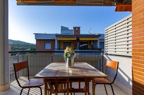 a wooden table with chairs and a vase of flowers on a balcony at Appartamento L'Approdo Trilo Rosso - MyHo Casa in Marina di Montenero