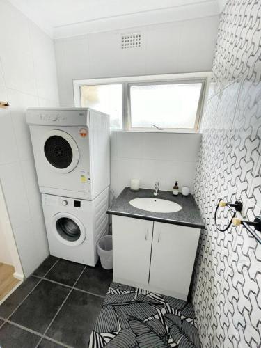 a bathroom with a sink and a washing machine at Lazur 24 Wilderness in Wilderness