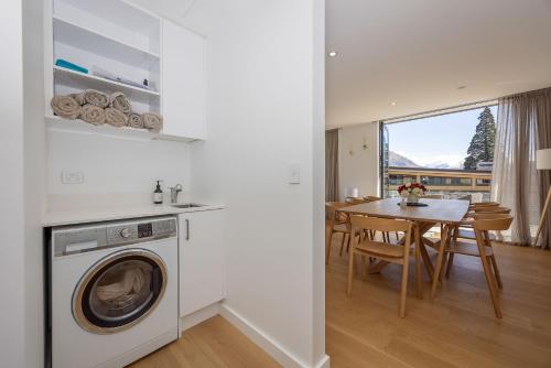 a kitchen and dining room with a washing machine and a table at Marina Views - Luxury Apartment in Wanaka