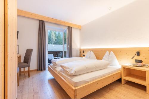 a bedroom with a bed and a desk and a window at Hotel Central in Nova Levante