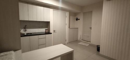 a kitchen with white cabinets and a sink at Apartemen Grand Kamala Lagoon Studio By Bonzela Property in Bekasi