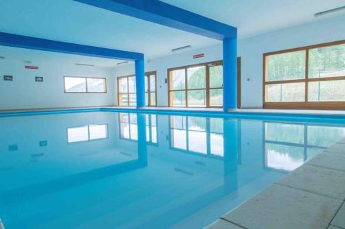 une piscine vide avec des pôles bleus dans l'eau dans l'établissement Sous les toits des Orres, aux Orres