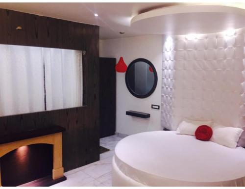 een slaapkamer met een wit bed en een spiegel bij Hotel The Royal, Sehore in Sehore