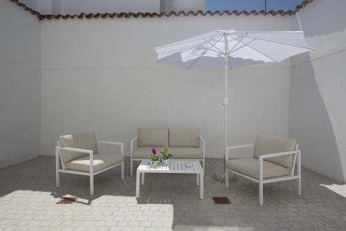 a room with three chairs and a table with an umbrella at Hostal Emeritae in Merida