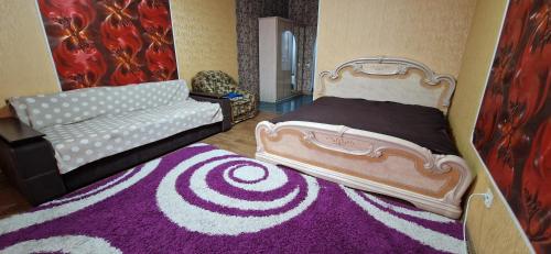 クロプィウヌィーツィクィイにあるЯновского 1к средняяのベッドルーム1室(ベッド1台、ソファ1台、紫色のラグ付)