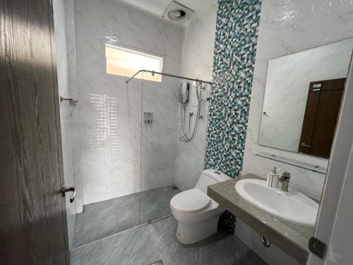 La salle de bains est pourvue de toilettes, d'un lavabo et d'une douche. dans l'établissement River Grand Hotel, à Hat Yai