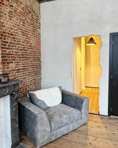 a couch in a living room with a brick wall at LouLou Home's in Antwerp