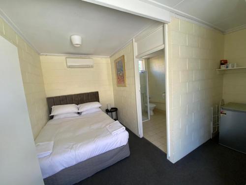 a bedroom with a white bed and a bathroom at Broken Hill Hotel in Boulder