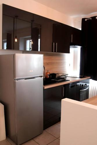 une cuisine avec un réfrigérateur en acier inoxydable et des armoires noires dans l'établissement La Factory - Centre - 4pers - Rêve Au Mans, au Mans