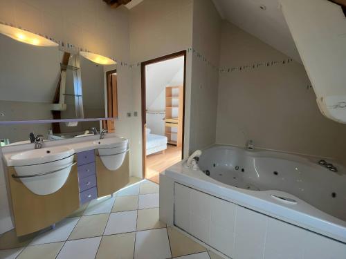 une salle de bain avec deux lavabos, une baignoire et un miroir dans l'établissement L'Ecolière - Villa Piscine Chauffée - Rêve au Mans, à Teillé