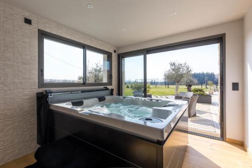 eine große Badewanne in einem Zimmer mit großen Fenstern in der Unterkunft Le Yucca Spa -Campagne-Jacuzzi- 8p - Rêve au Mans 