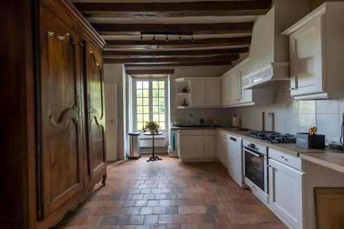 une cuisine avec des armoires blanches et un sol carrelé dans l'établissement Château de l'Aubonnière -Nature-14p- Rêve au Mans, à Villiers-au-Bouin