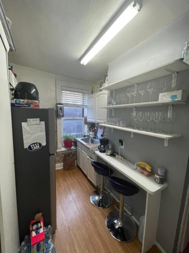uma cozinha com um frigorífico e um balcão com bancos de bar em Room in a 2 Bedrooms apt. 10 minutes to Time Square! em West New York