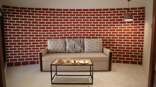 a living room with a couch against a brick wall at Jagira Ananta Elite , Sasan Gir in Chitrod