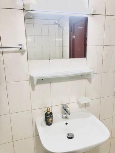 a white bathroom with a sink and a mirror at Private Room in Dubai-Sharjah Border in Sharjah