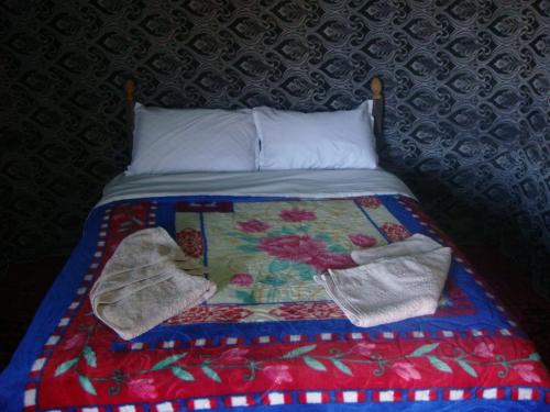 a bed with two mittens and a quilt on it at Honeymoon Luxury Glamping in Adrouine