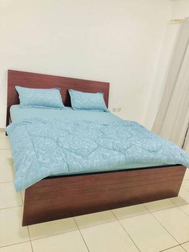 a bed with blue comforter and pillows on it at Private Room in Dubai-Sharjah Border in Sharjah