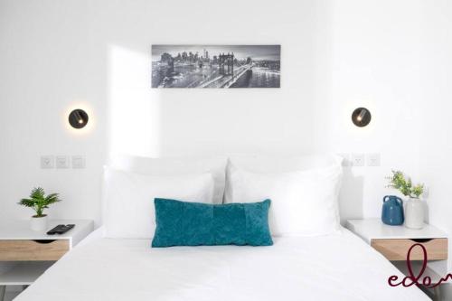 a white bedroom with a white bed with a blue pillow at דירת חדר שינה וסלון עם מרפסת ליד הים - By Edomlux in Eilat