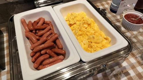 two trays of hot dogs and scrambled eggs on a table at HOTEL VINE OSAKA KITAHAMA in Osaka