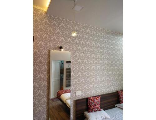 a bedroom with a wall covered in wallpaper at Geeta Lodge, Solapur in Solapur