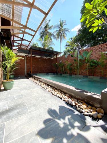 una piscina en un patio trasero con un edificio de ladrillo en Kutum's Wooden House - Private Pool, Breakfast & Cafe en Huma