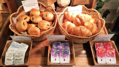 a display of baskets of bread and pastries on a table at HOTEL VINE OSAKA KITAHAMA in Osaka