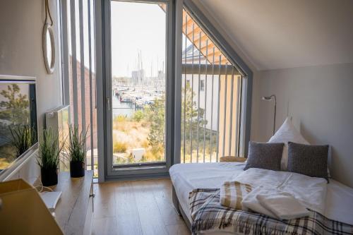 a bedroom with a bed and a large window at Ostsee - Reetdachhaus Nr 44 "Reethüs - Marina" im Strand Resort in Heiligenhafen