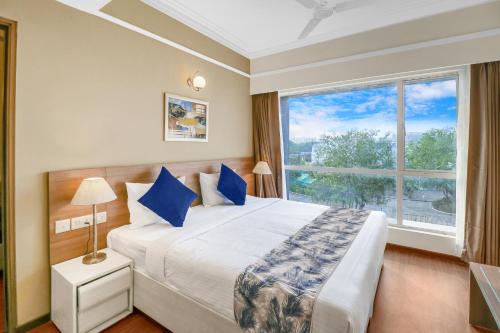 a bedroom with a bed and a large window at Starlit Suites Newtown Kolkata in kolkata