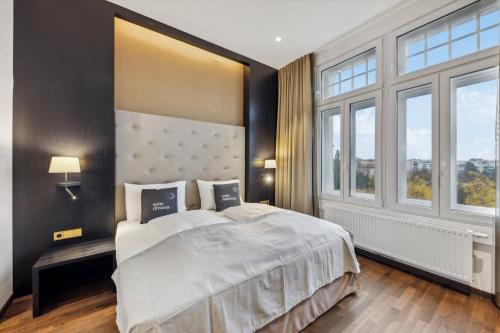 a bedroom with a large bed and large windows at Limehome Vienna Roßauer Lände in Vienna