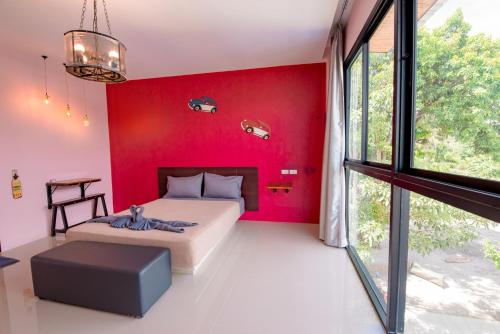 um quarto com paredes vermelhas, uma cama e uma janela em เเองเจล่า รีสอร์ท em Pran Buri
