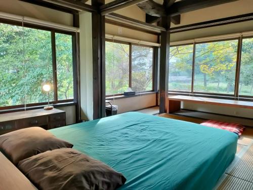 um quarto com uma cama grande em frente às janelas em Antique Villa Lotus（古民家ロータス） em Tsukuba