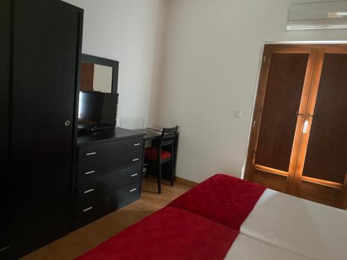 a bedroom with a bed and a dresser with a television at Casa do Ti Latoeiro in Torre de Moncorvo