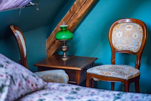 a green lamp sitting on a table next to two chairs at Dawny Dom in Płoty