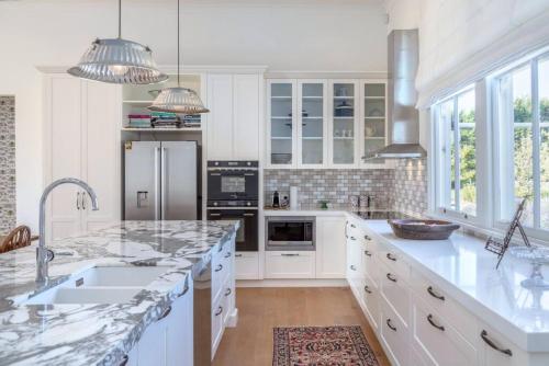 a kitchen with white cabinets and marble counter tops at The White House, Martinborough in Martinborough 