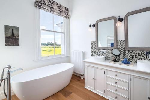 a white bathroom with a large tub and two mirrors at The White House, Martinborough in Martinborough 